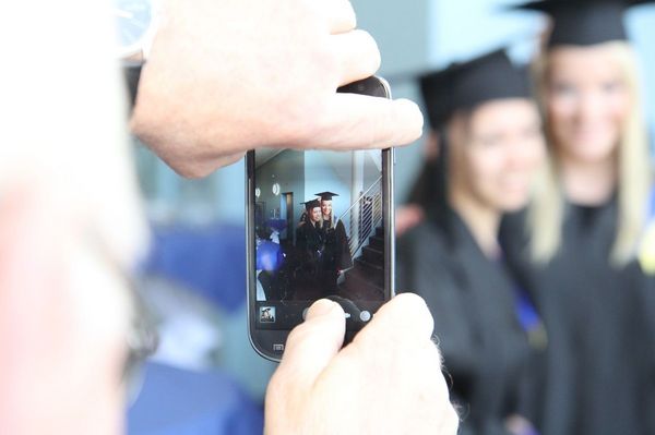Zwei Absolventinnen werden mit Smartphone fotografiert
