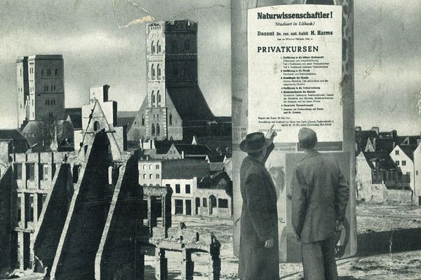 Litfaßsäule mit Plakat, davor zwei Männer